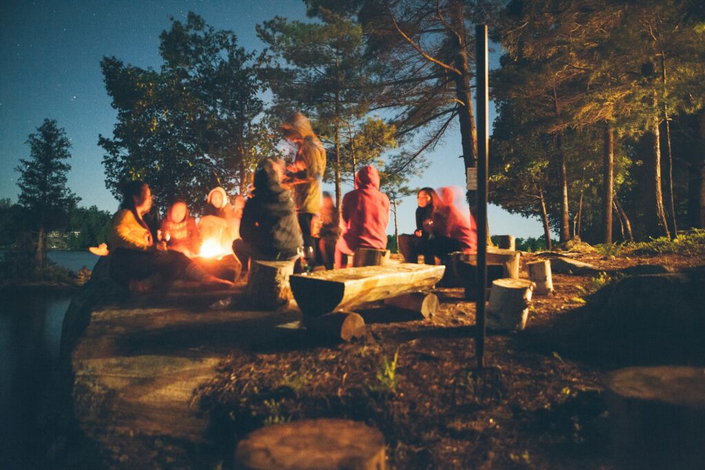 A group of people gathered around a campfire at dusk.